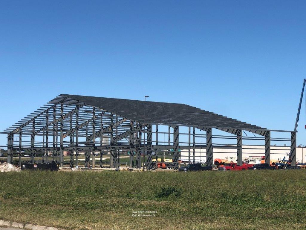 A large metal structure is being built in a grassy field.