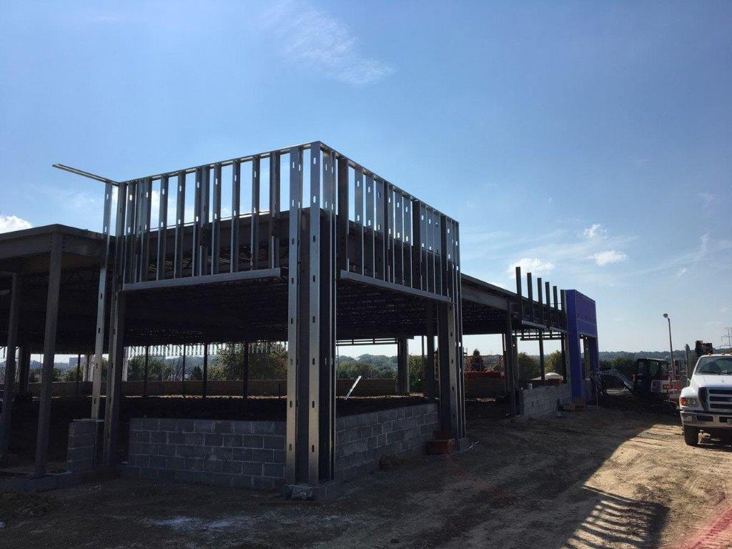 A white van is parked in front of a building under construction.
