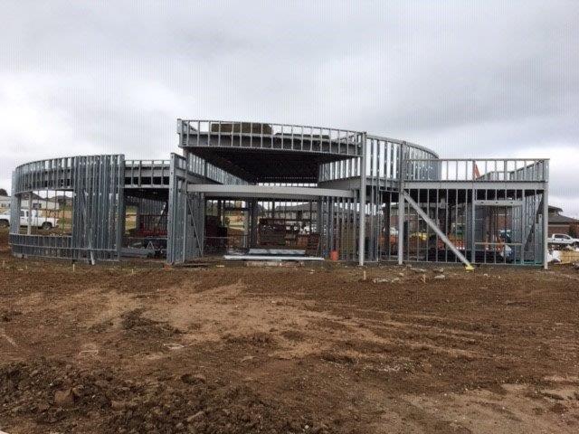 A large metal structure is being built in a dirt field.