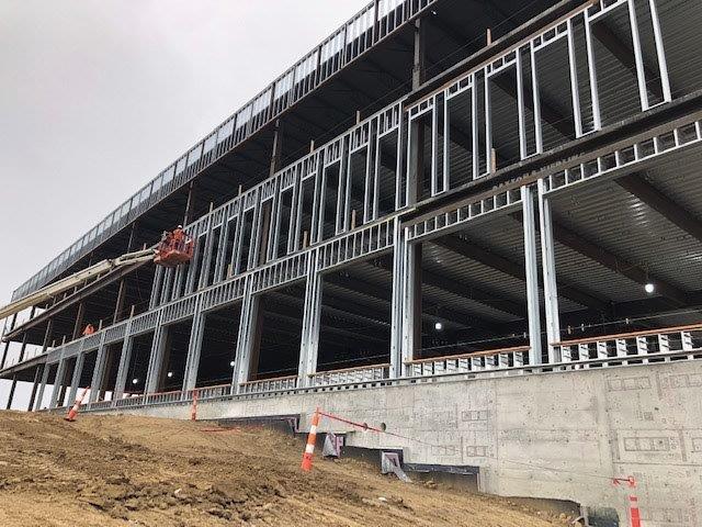 A large building is being built on top of a dirt hill.