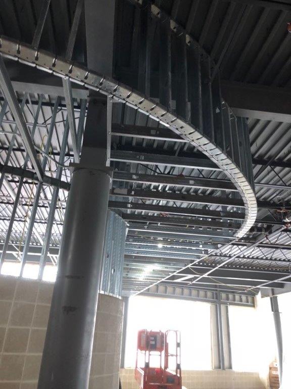 The ceiling of a building is being built and there is a forklift in the background