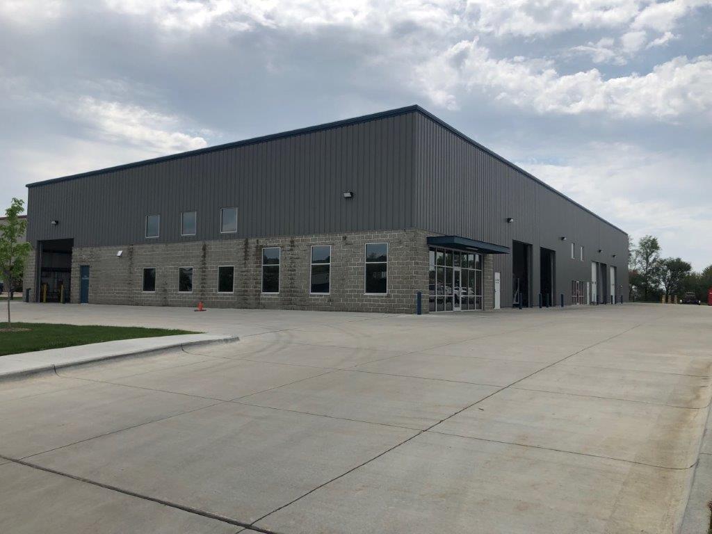 A large building with a lot of windows and a concrete driveway in front of it.