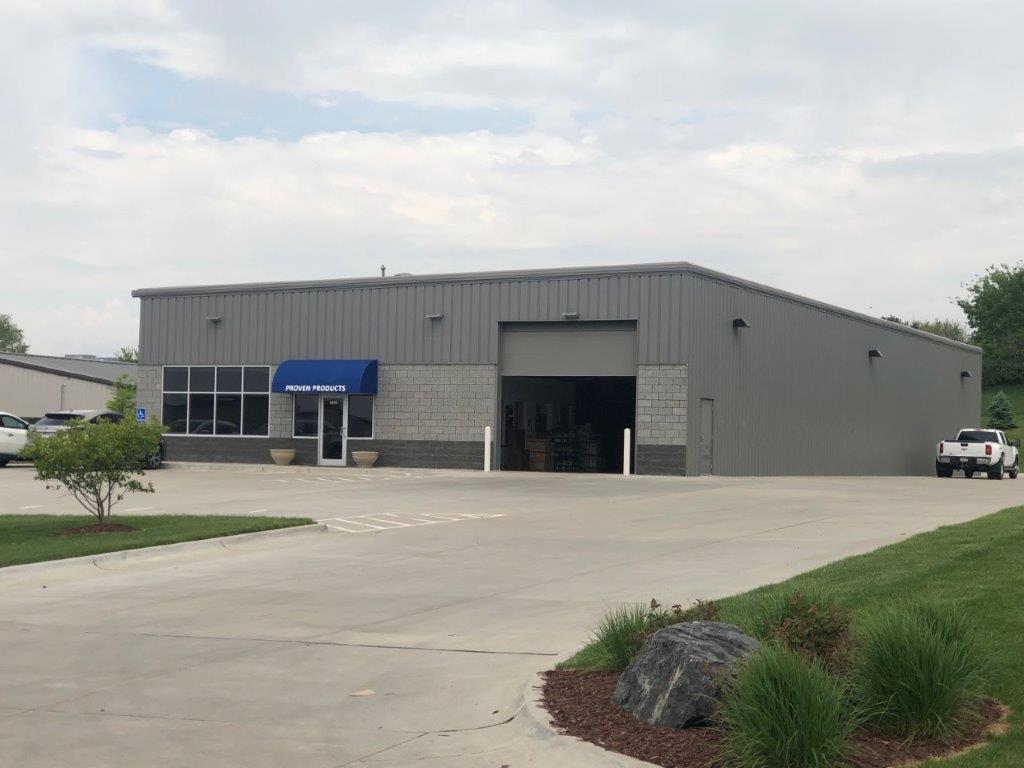 A large gray building with a blue awning and a white truck parked in front of it.