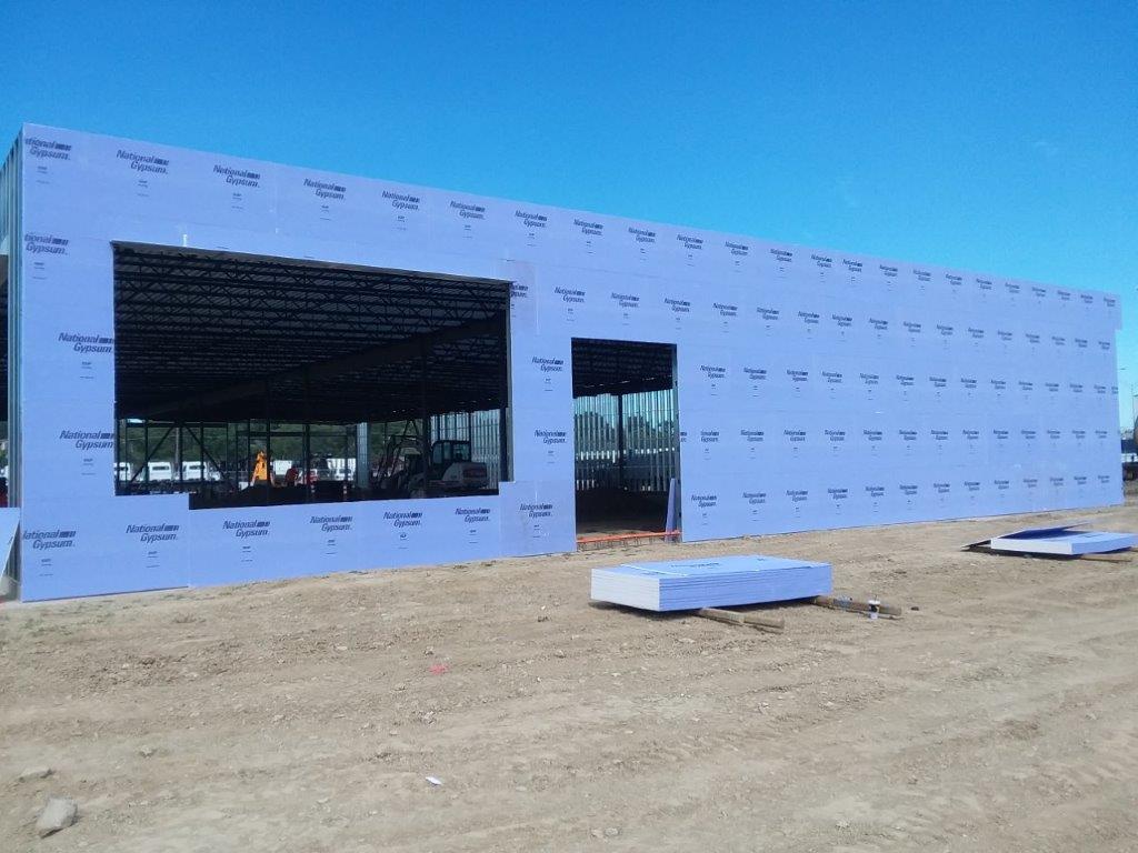 A large building is being built in the middle of a dirt field.
