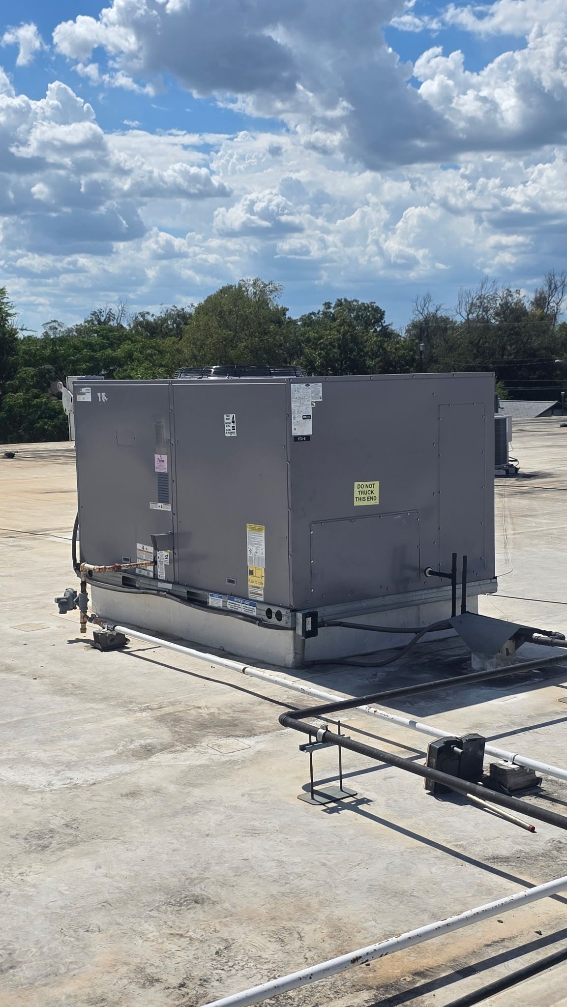 Gray industrial HVAC unit on a rooftop under a partly cloudy sky.