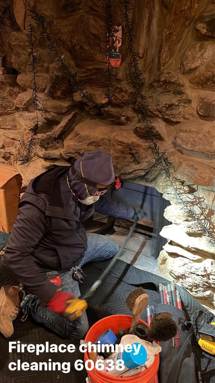 Person cleaning a fireplace chimney in a stone-walled area. They are wearing protective gear.