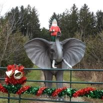 A statue of an elephant with a Santa Claus figure riding on top, decorated for Christmas.