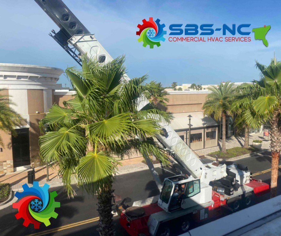 Red crane truck lifting near palm trees outside SBS-NC commercial HVAC services building