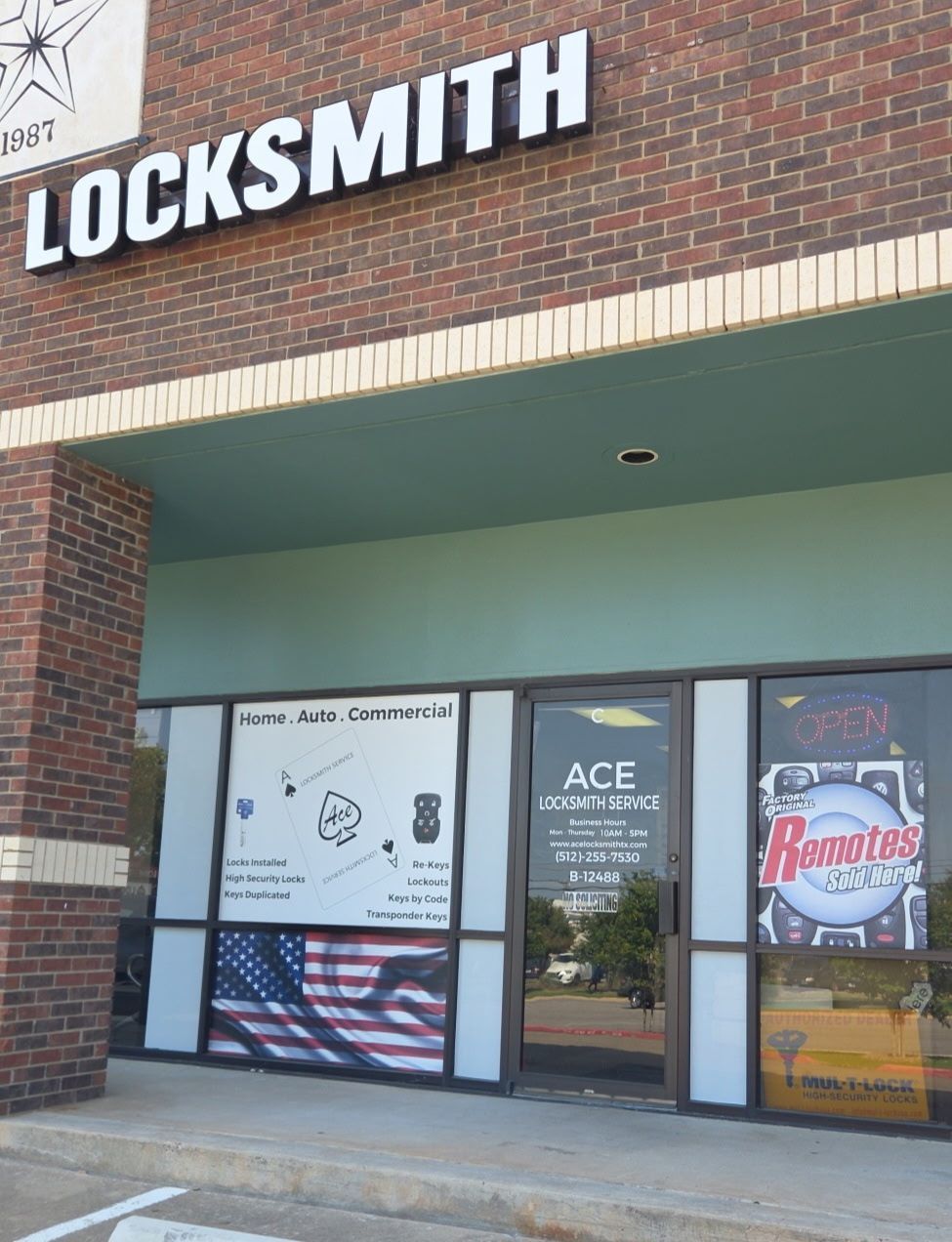 Exterior of Ace Locksmith store with signage, red brick, and American flag graphic on the window.