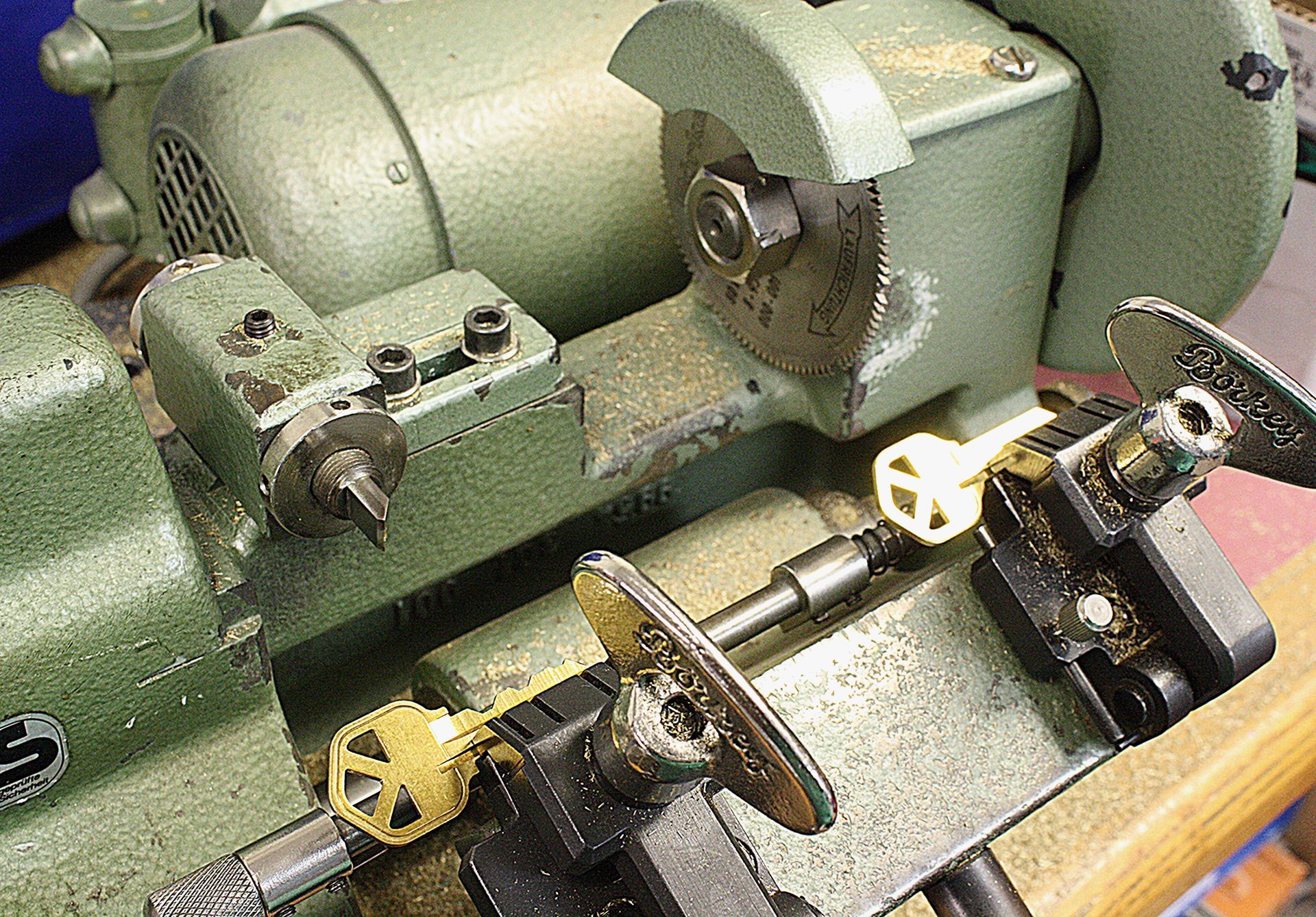 Key-cutting machine with two keys, one being copied. Green metal and yellow keys.