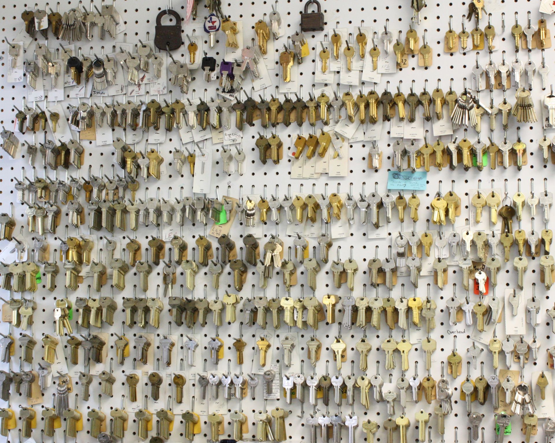 Wall covered with rows of various metal keys hanging on a pegboard, possibly at a locksmith shop.