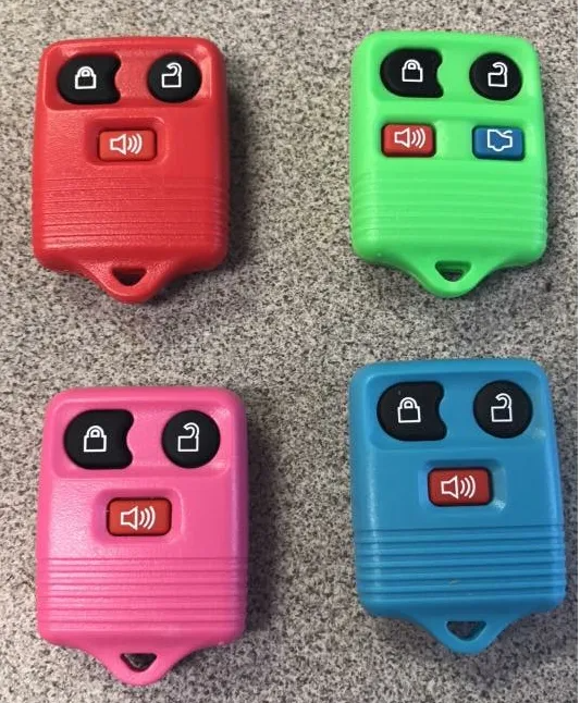 Four colorful car key fobs: red, green, pink, and blue on a gray surface. Each has three buttons.