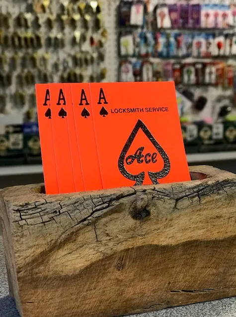 Four orange playing cards with ace of spades design in a wooden holder, 