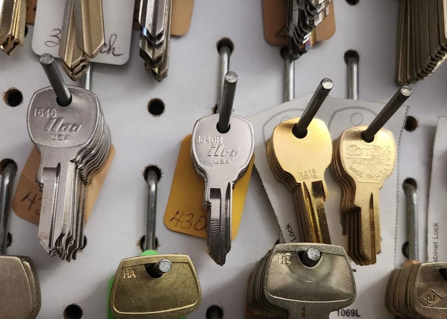 Keys hanging on a pegboard, with tags. Various metal colors, silver and gold, indicating different types