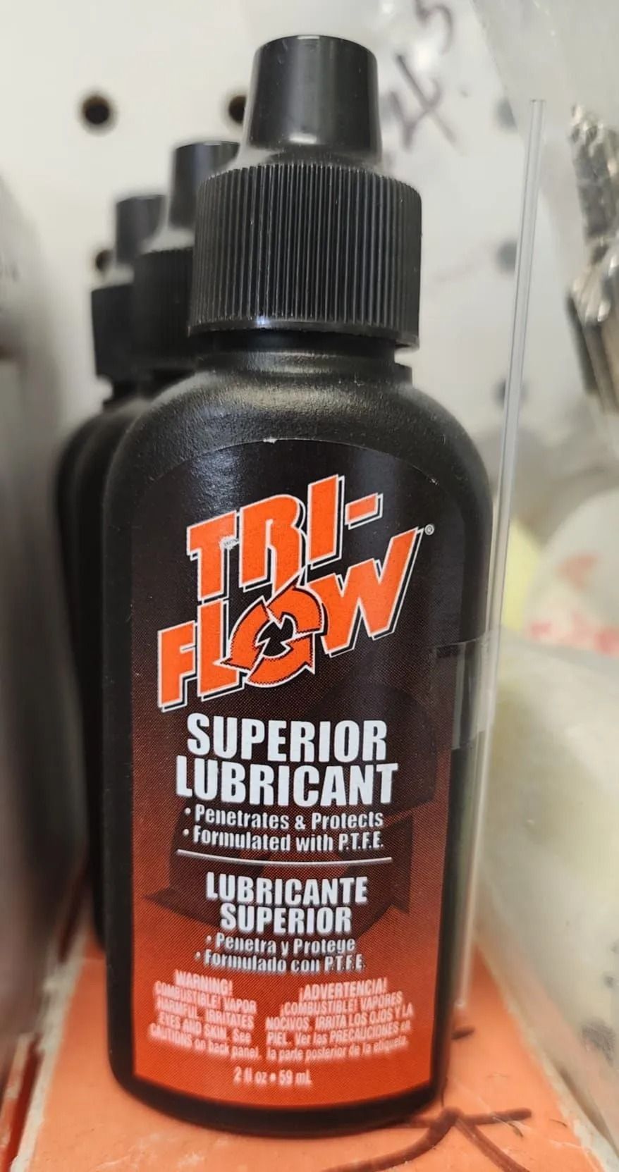 Tri-Flow Superior Lubricant bottle, black and orange label, stands in a row with others