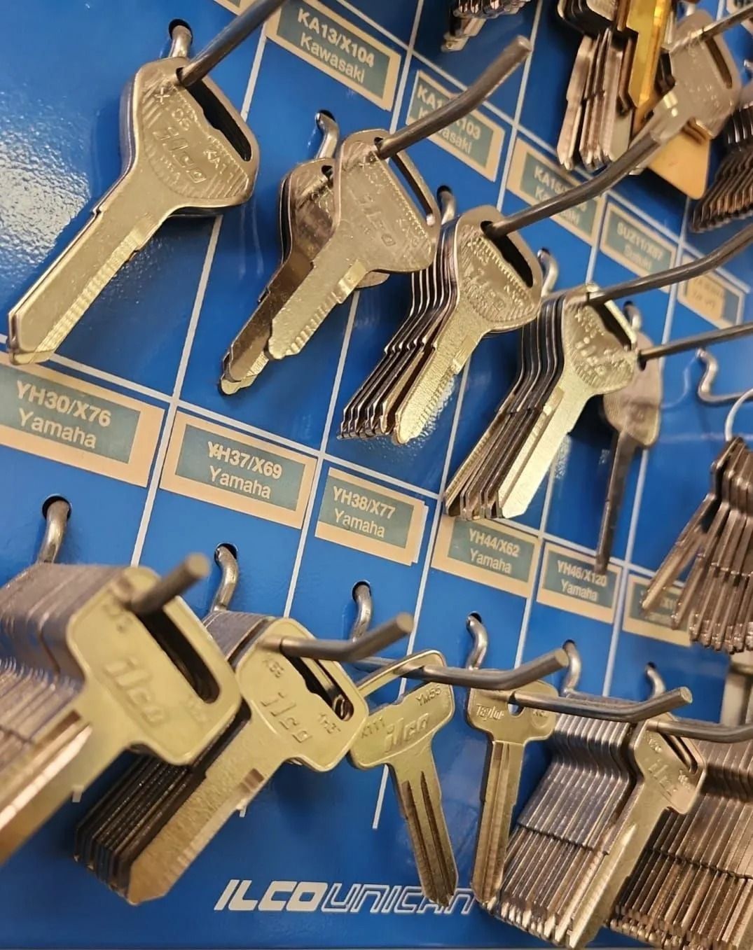 Key blanks on a blue pegboard, arranged alphabetically, with the ILCO Unican logo