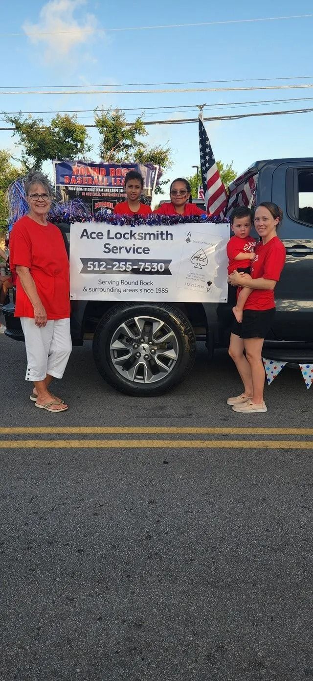 People stand with a banner in front of a truck at a parade. The banner promotes a locksmith service
