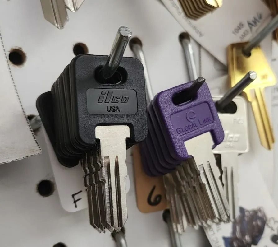 Two stacks of blank keys on a pegboard. Black and purple key heads, with key blanks below