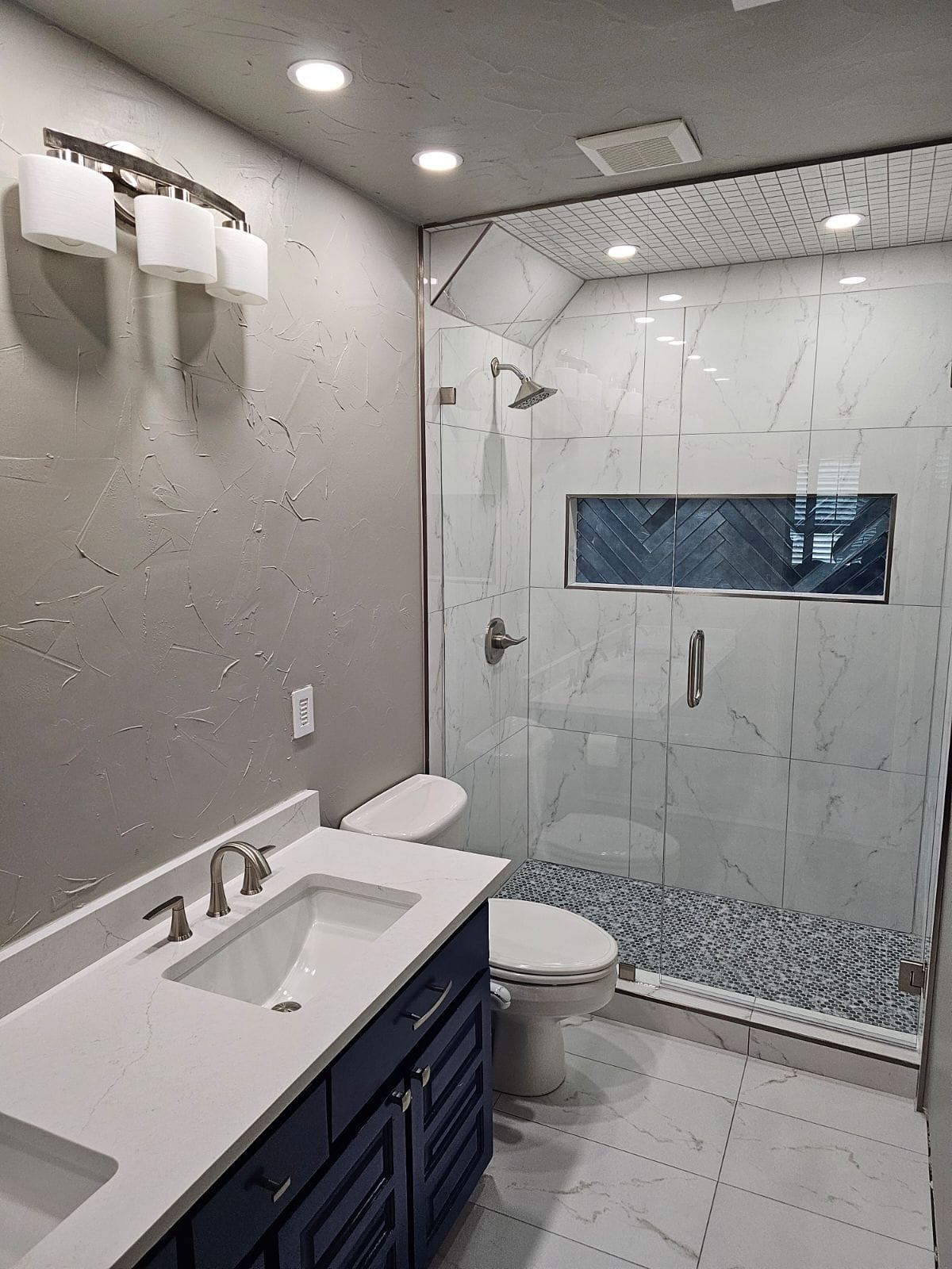 A bathroom with a sink , toilet and walk in shower.