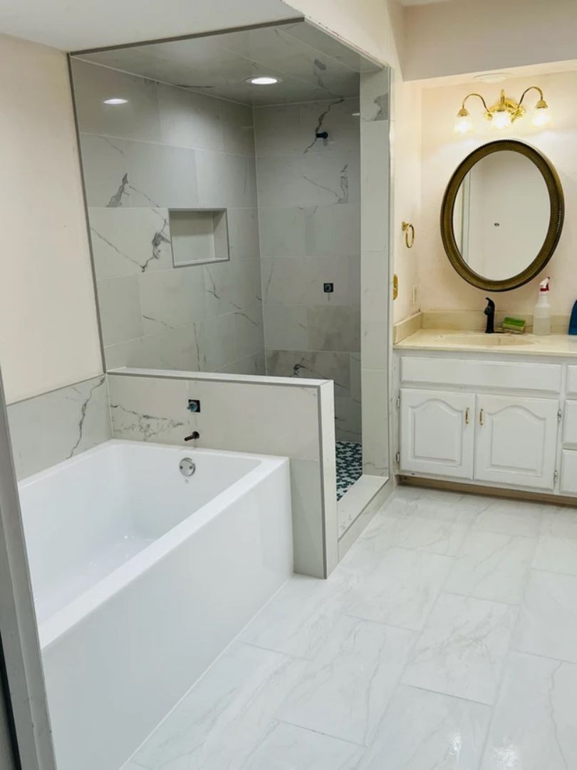 A bathroom with a bathtub, sink, mirror and shower.