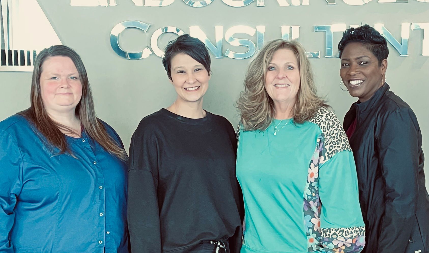 A group of women are posing for a picture in front of a sign that says consulting.
