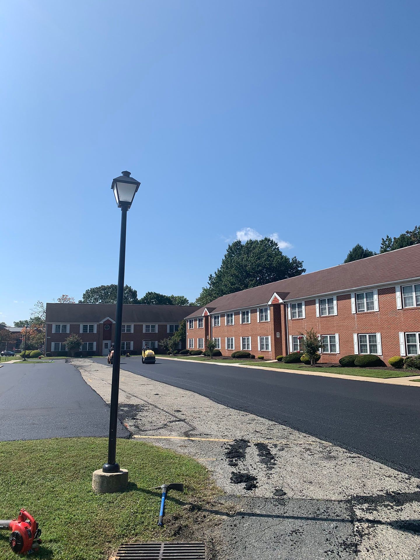 Residential street with brick apartment buildings, a lamppost, and a clear blue sky