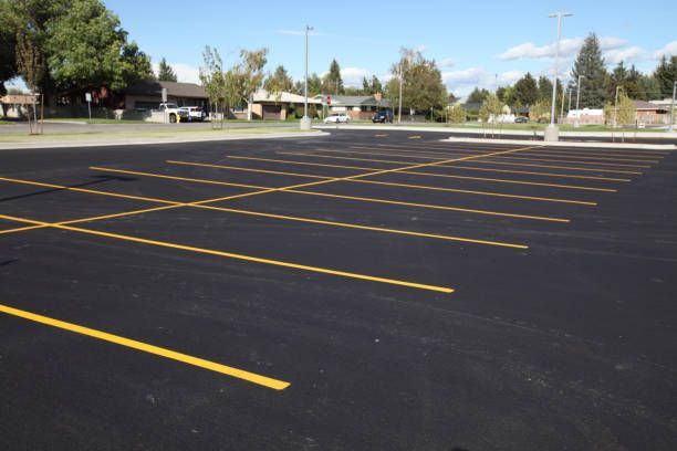 Empty blacktop parking lot with yellow painted lines under a blue sky