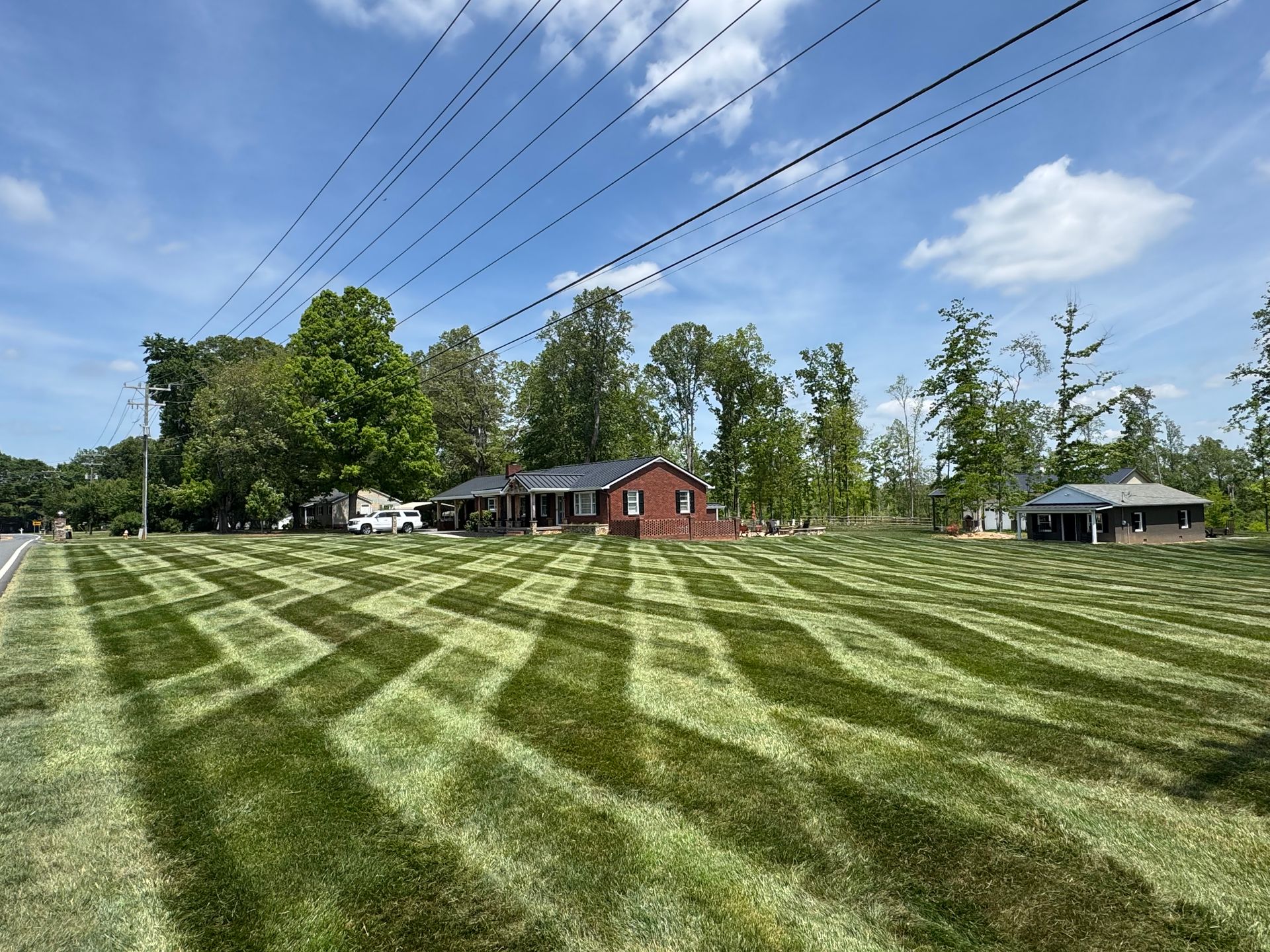 A lush green lawn with a red house in the background.