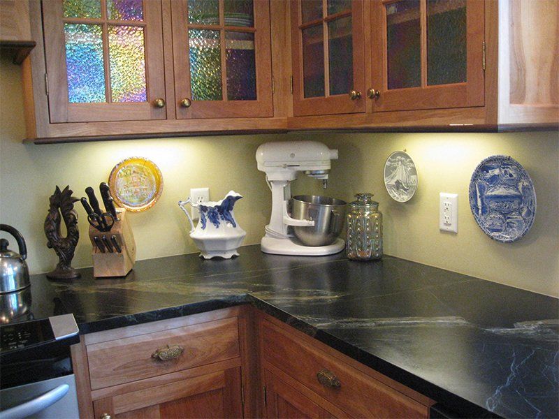 Kitchen counter with black countertop, wooden cabinets, and small decorative plates and appliances.