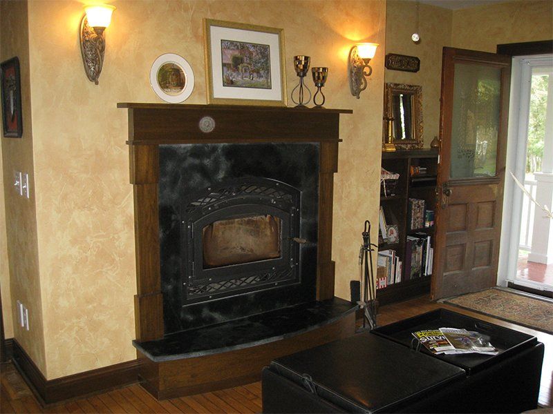 Cozy living room with a black fireplace, wall sconces, and an open door to the outside.