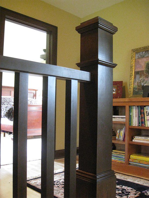 Dark wooden stair railing post beside a doorway in a home interior