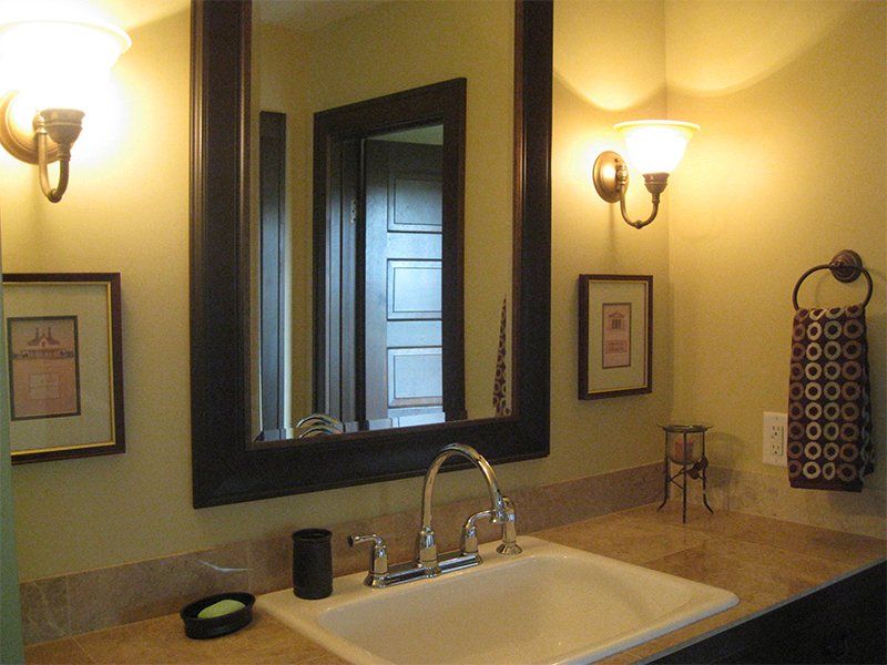 Bathroom vanity with mirror, sink, wall sconces, and beige countertop.