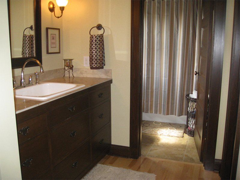 Bathroom vanity with sink, dark cabinets, and a striped curtain over a doorway.