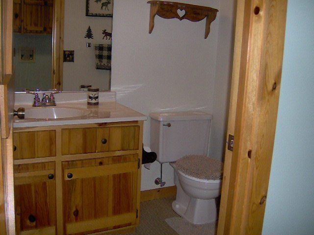 Small bathroom with wooden vanity, white sink and toilet, and a wall mirror.