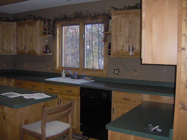 Cozy kitchen with wooden cabinets, green countertops, and a window over the sink