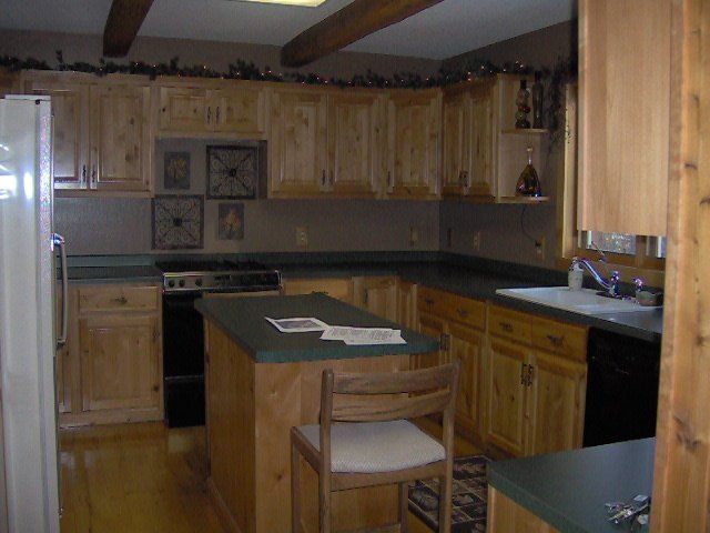 Wooden kitchen with island, cabinets, and black appliances in a warm, rustic interior