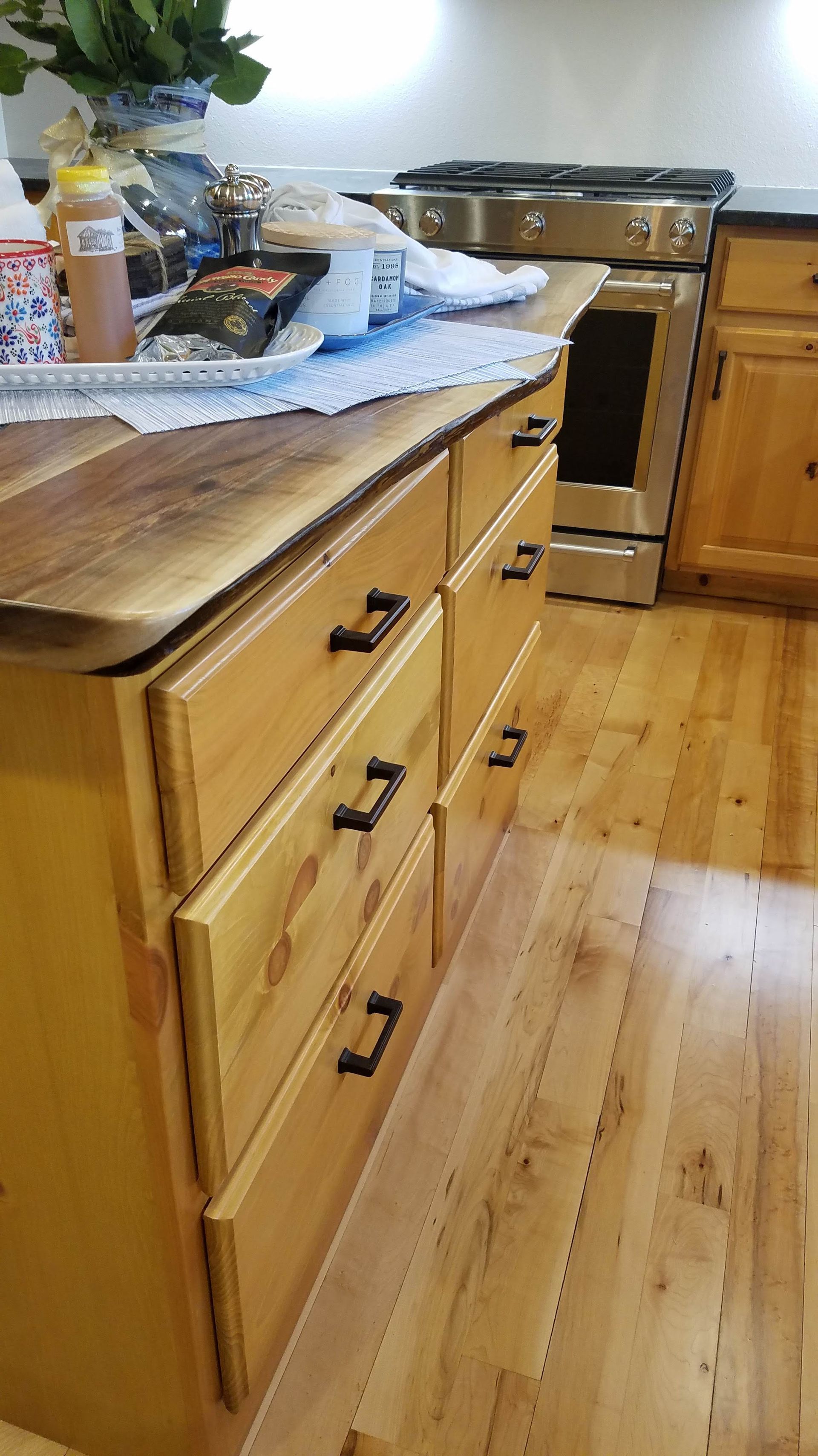 Kitchen with wooden cabinets, countertop items, and a stove on a hardwood floor.
