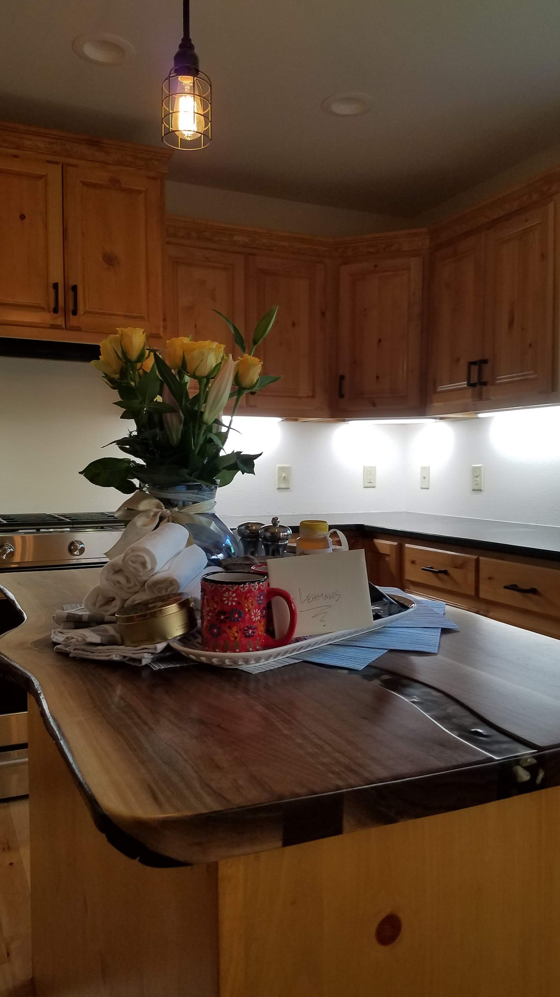 Kitchen with wooden cabinets and island, decorated with flowers and a red pitcher centerpiece.