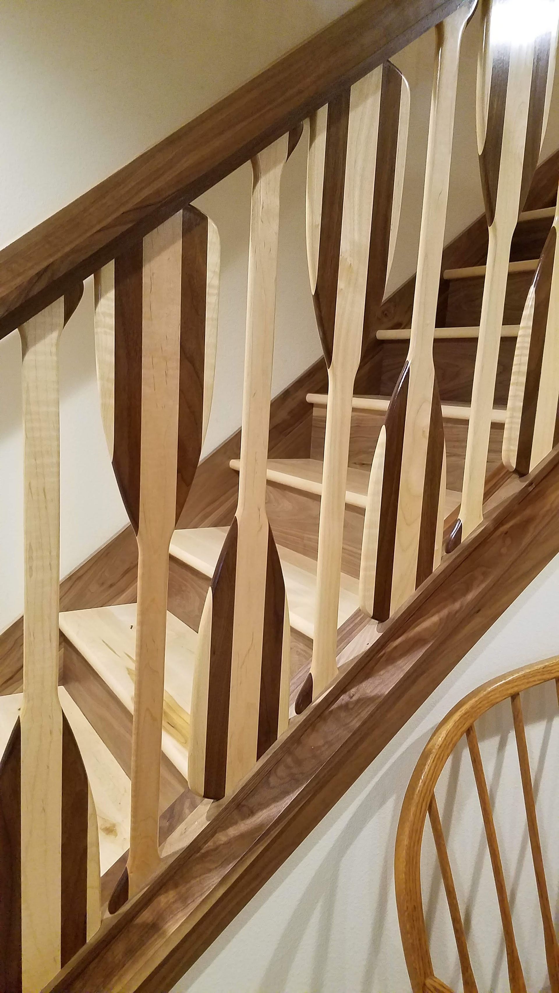 Wooden staircase railing with beige carpeted steps and a dining chair in the foreground