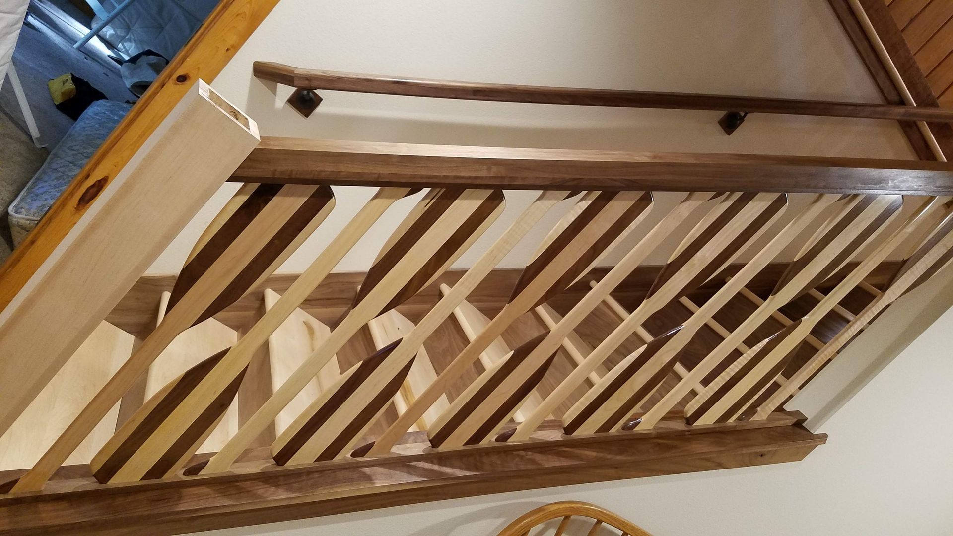 Wooden loft railing and open ceiling beams inside a home, viewed at an angle