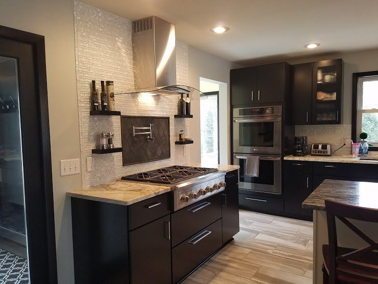 Modern kitchen with dark cabinets, granite counters, stainless appliances, and a tiled backsplash