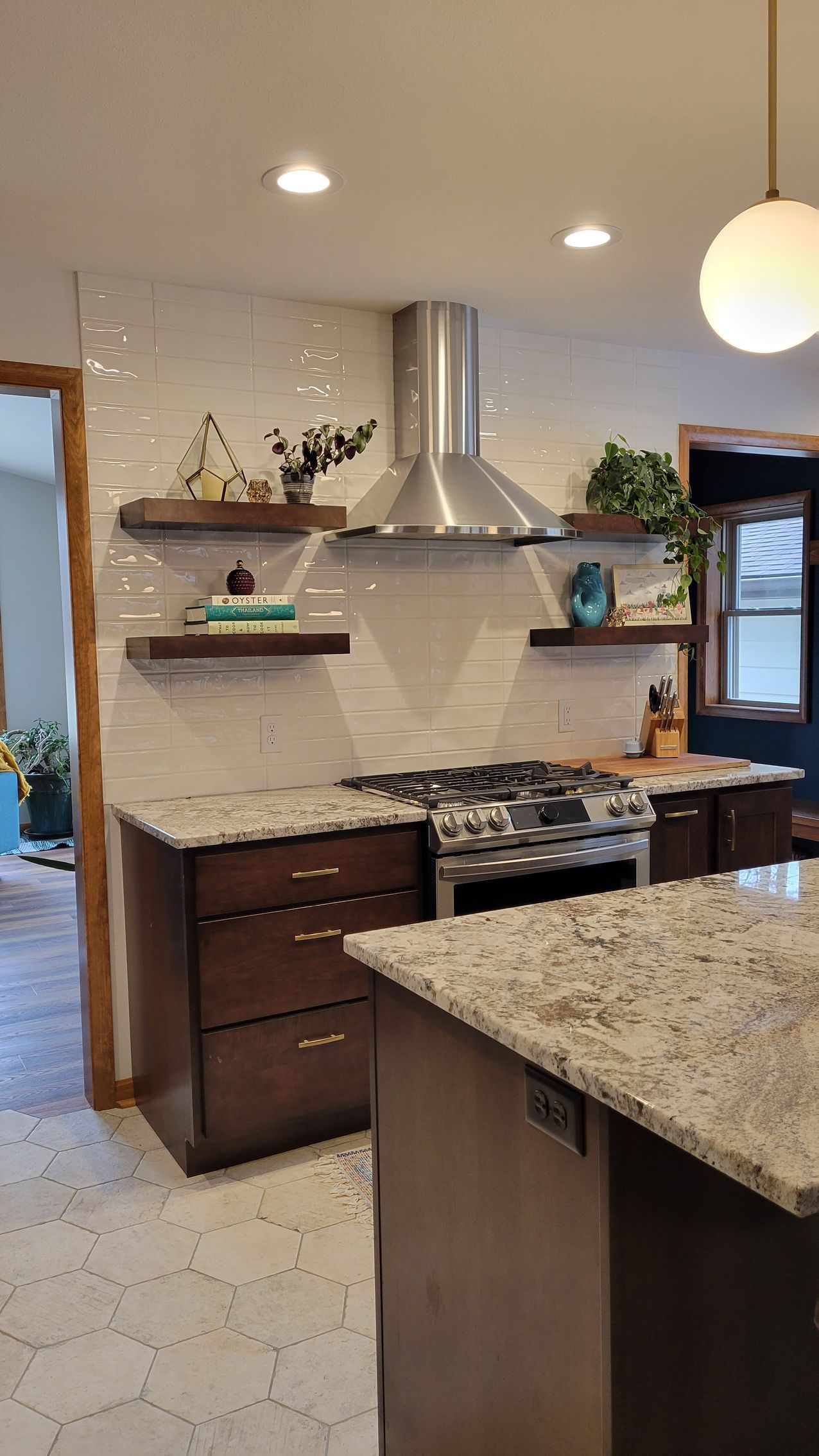 Modern kitchen with stainless steel range hood, white tile backsplash, and dark wood cabinets.
