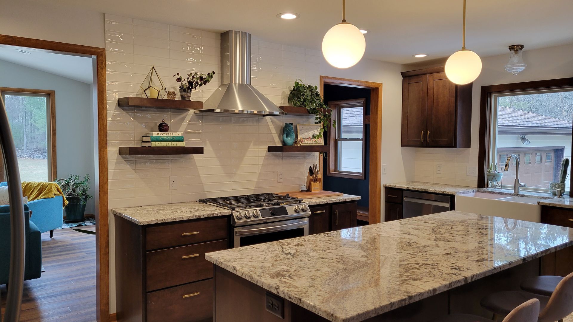 Modern kitchen with dark wood cabinets, white backsplash, and granite countertops.