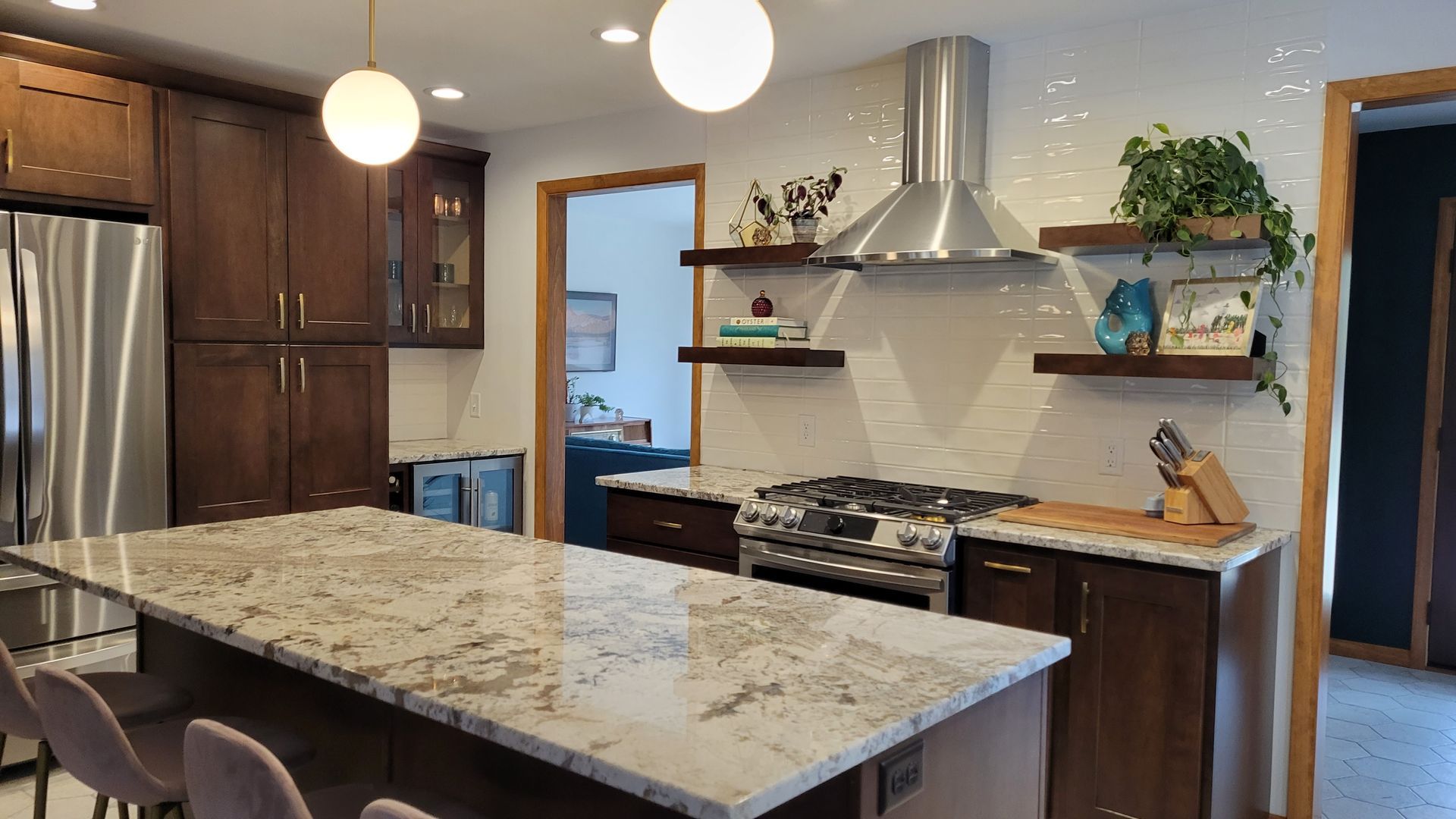 Modern kitchen with island and stainless steel appliances; dark wood cabinetry and white tile backsplash.