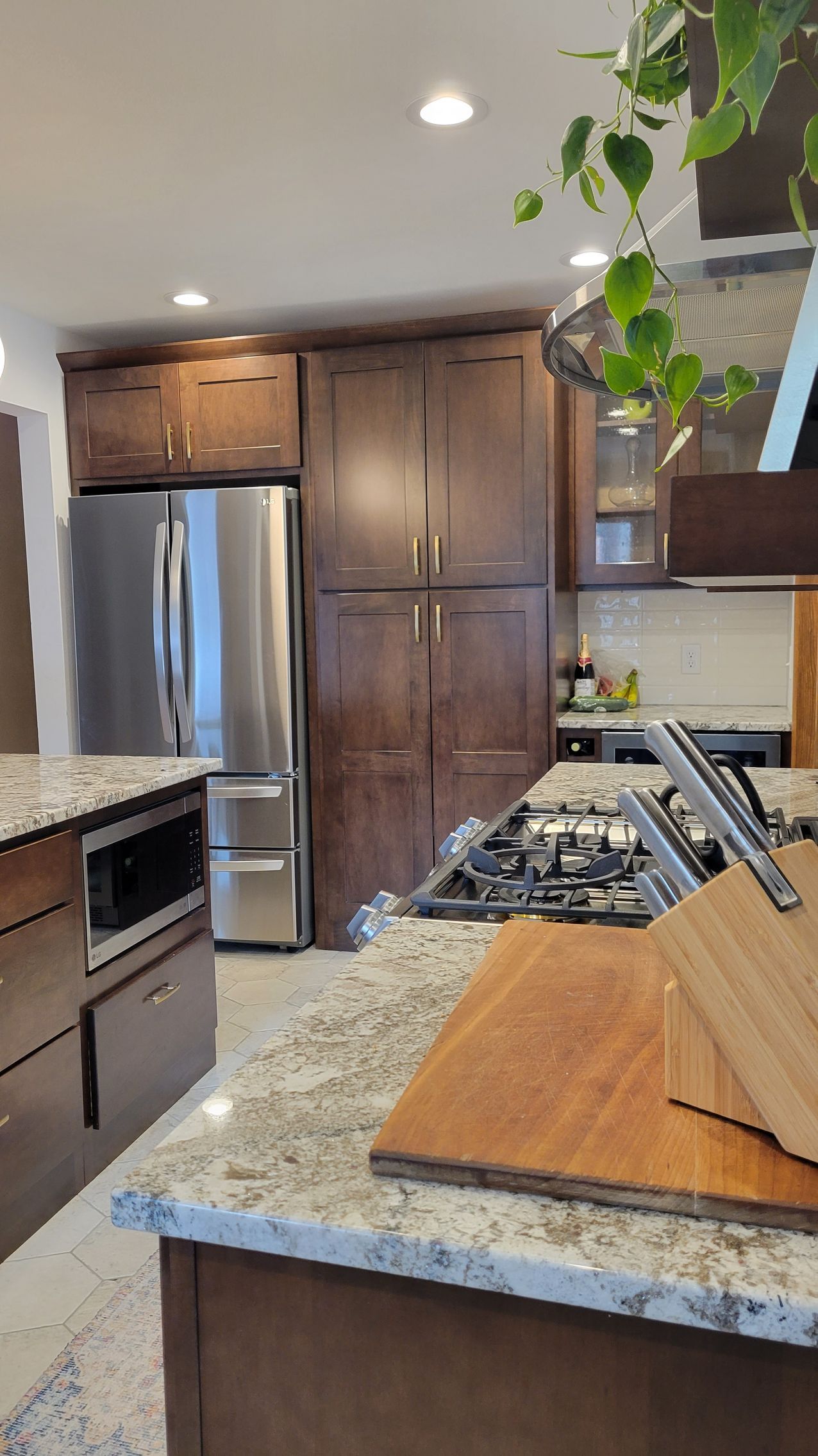 Kitchen with stainless steel refrigerator and dark wood cabinets, granite countertops.