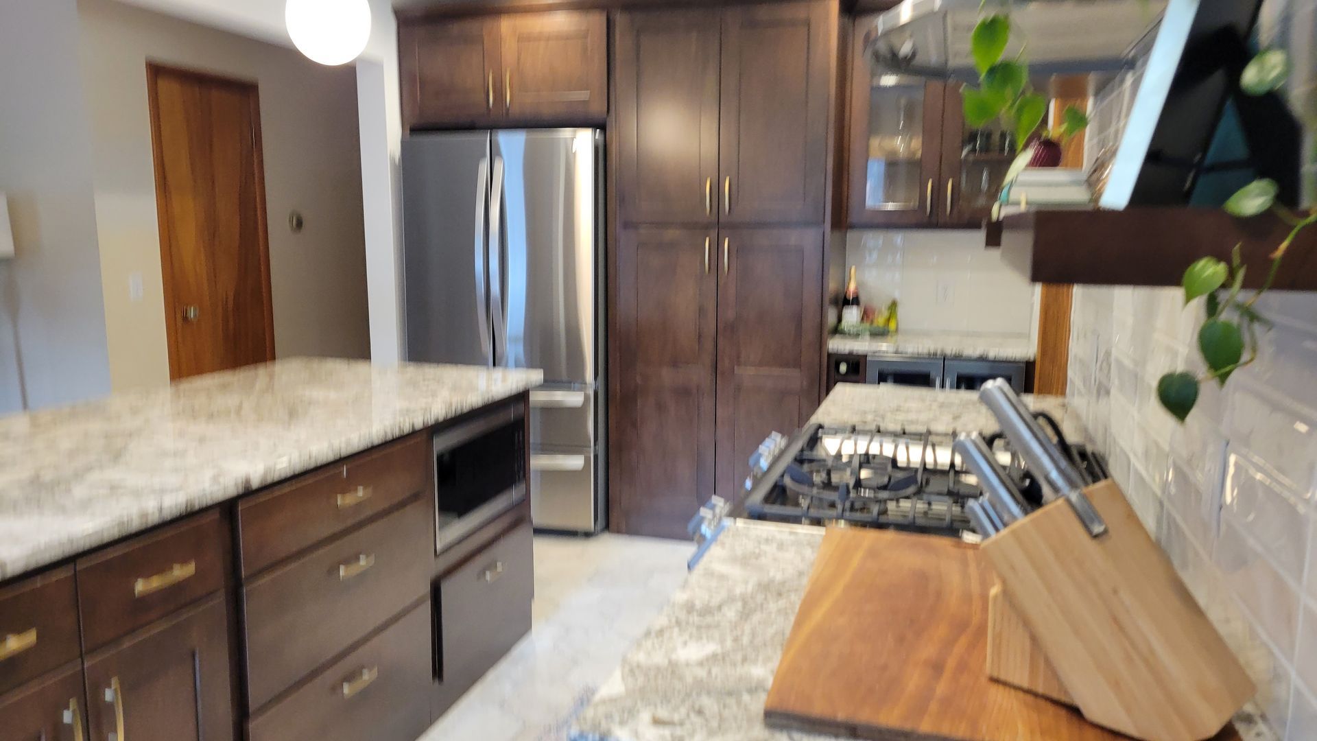 Kitchen with dark wood cabinets, stainless steel refrigerator, and granite countertops.