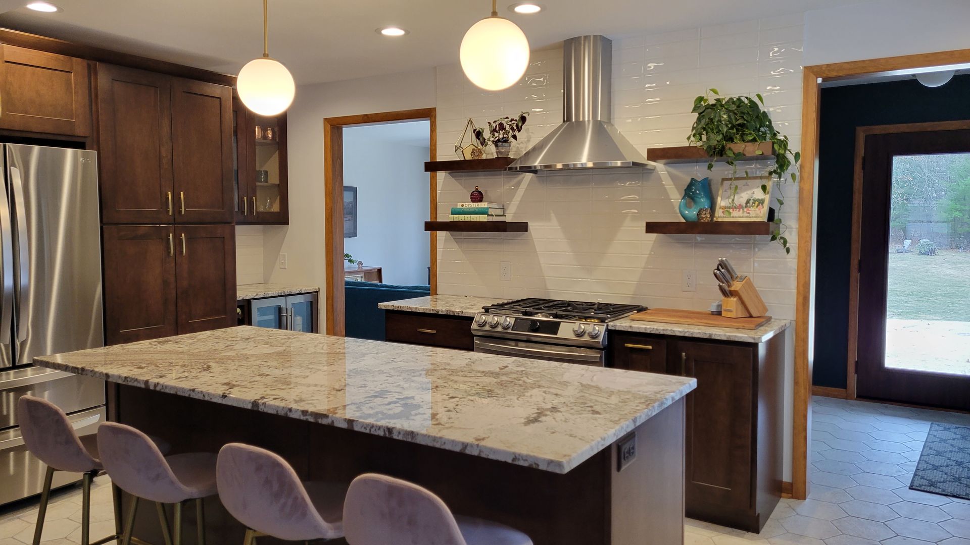 Kitchen with island, stainless steel appliances, dark wood cabinets, and two globe pendant lights.