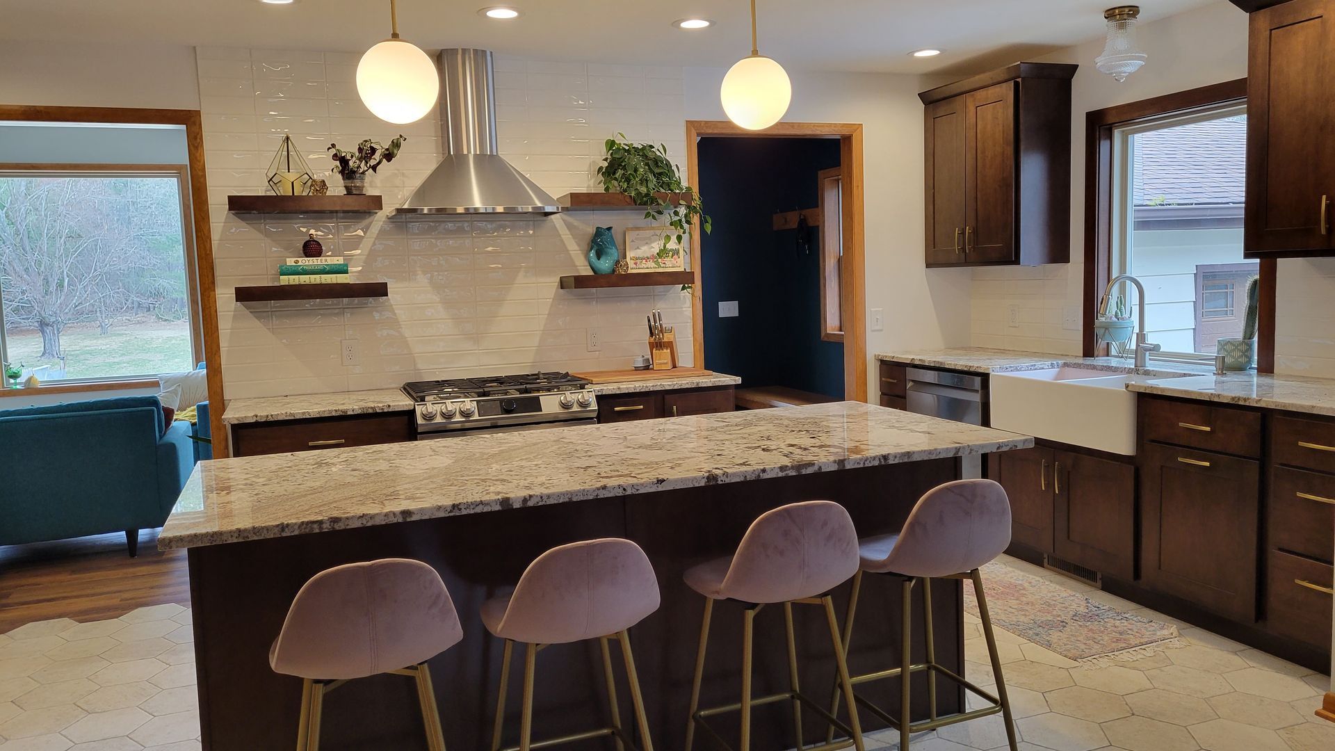 Modern kitchen with dark brown cabinets, granite countertops, and a central island with pink bar stools.