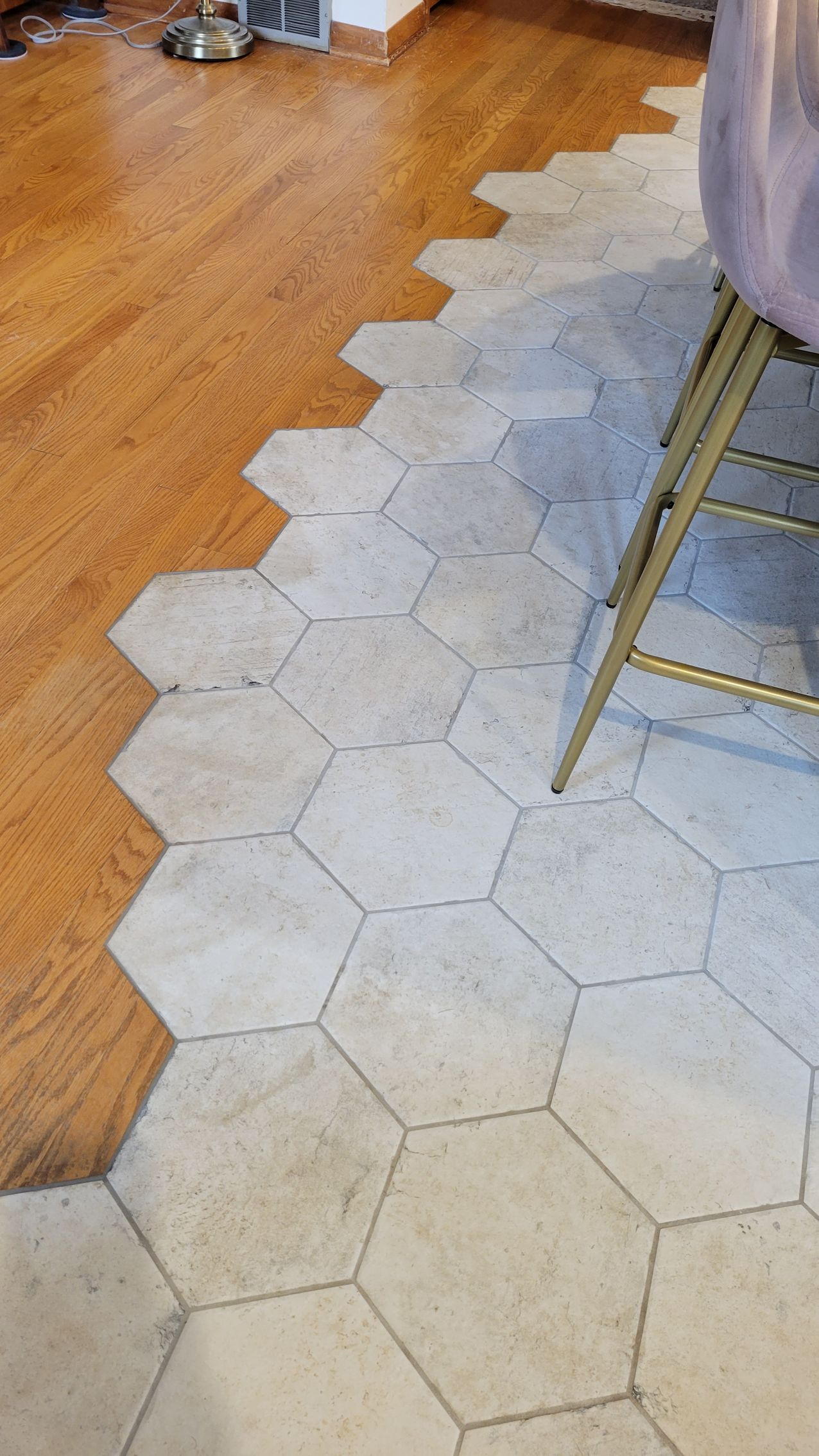 Hexagonal tile floor transitions to wood floor, with a golden chair leg partially visible.