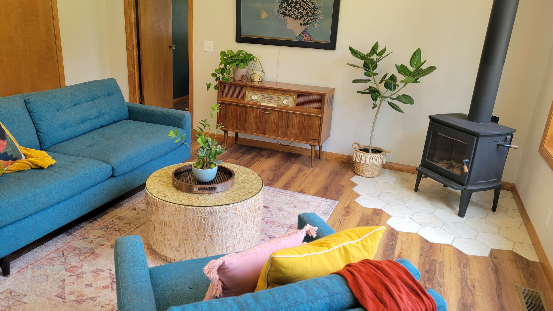 Living room with blue sofas, wooden furniture, plants, fireplace, and light pink rug.